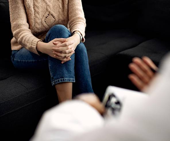 Elderly woman shaking hands with man sitting on couch