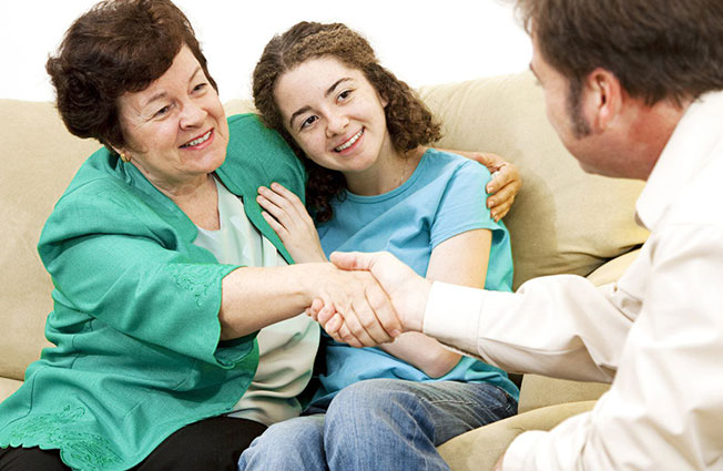 Elderly woman with young girl shaking hands with man